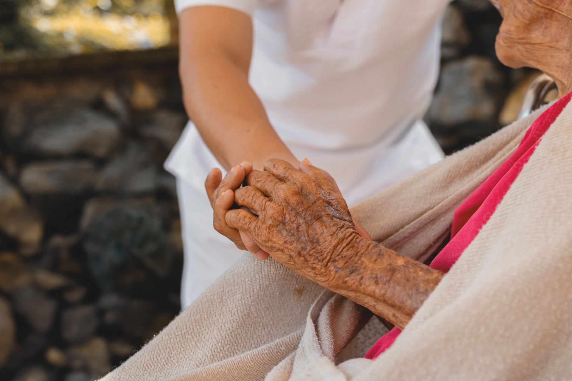 Close-Up of Senior Woman Holding Hands with Caregiver, Symbolizing Compassion and Support in Elderly Care